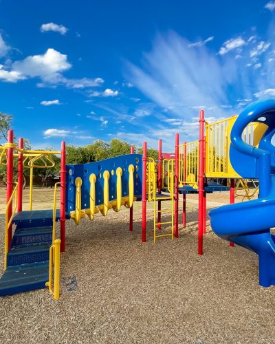 Colorful typical playground structure under sunny blue cloud sky at elementary school in Texas, America Colorful typical playground structure under sunny blue cloud sky at elementary school in Texas, America. Slides, stairs, swing with safety wood chips ground
